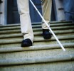 Blind man descending stairs, with the aid of a white cane (stick).